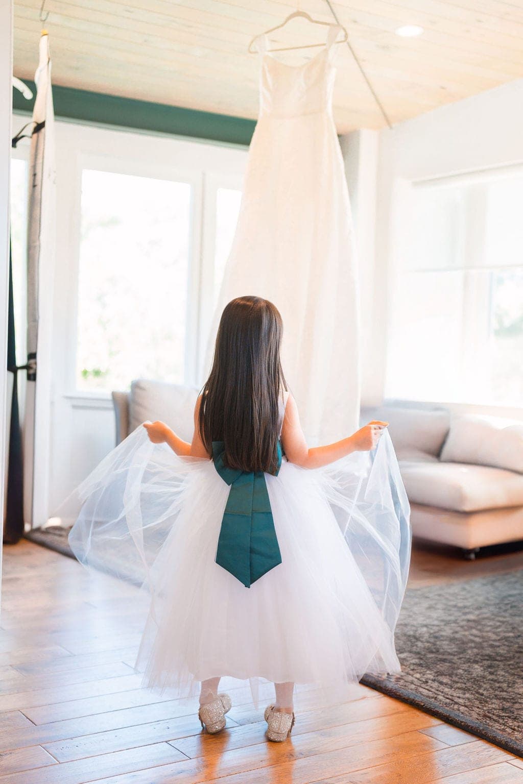 Flower girl twirling her tulle dress beneath a hanging wedding gown