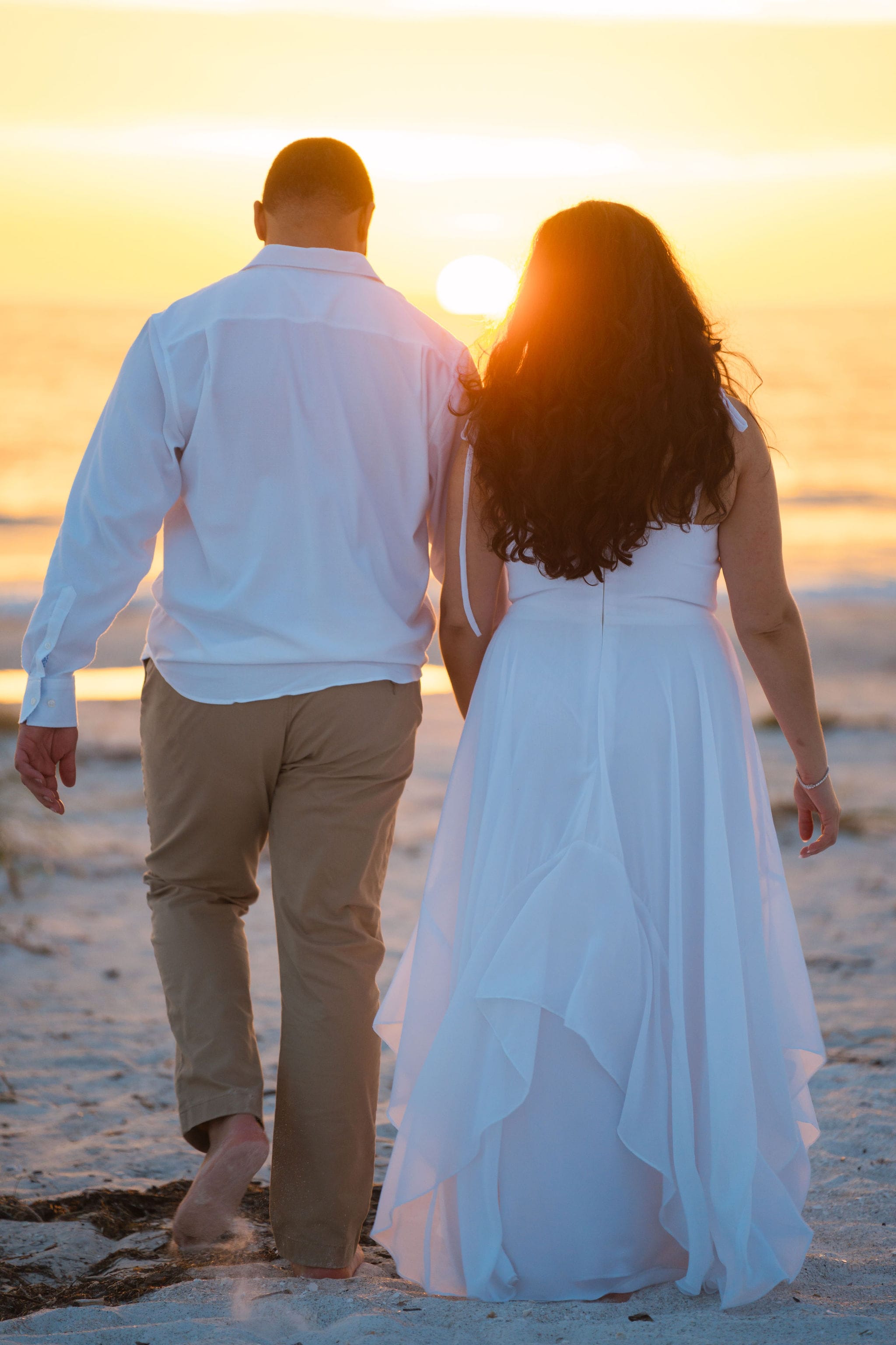 Couple walking into orange sunset beach