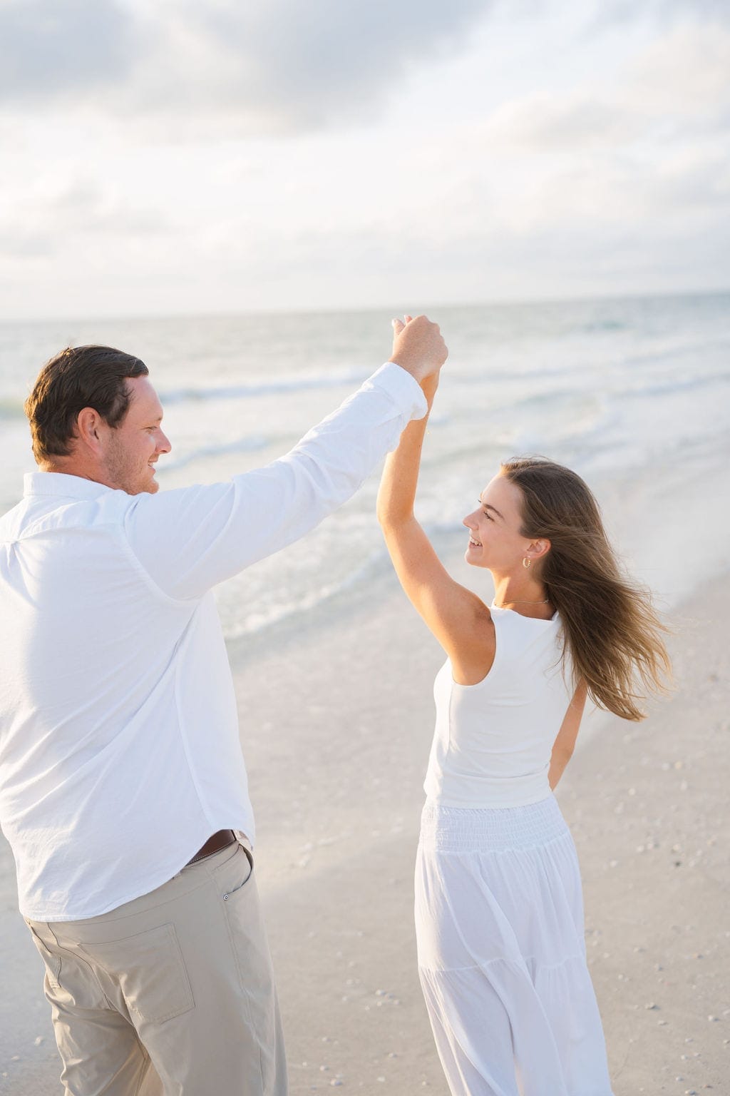 Fiance twirling partner white dress gulf coast beach