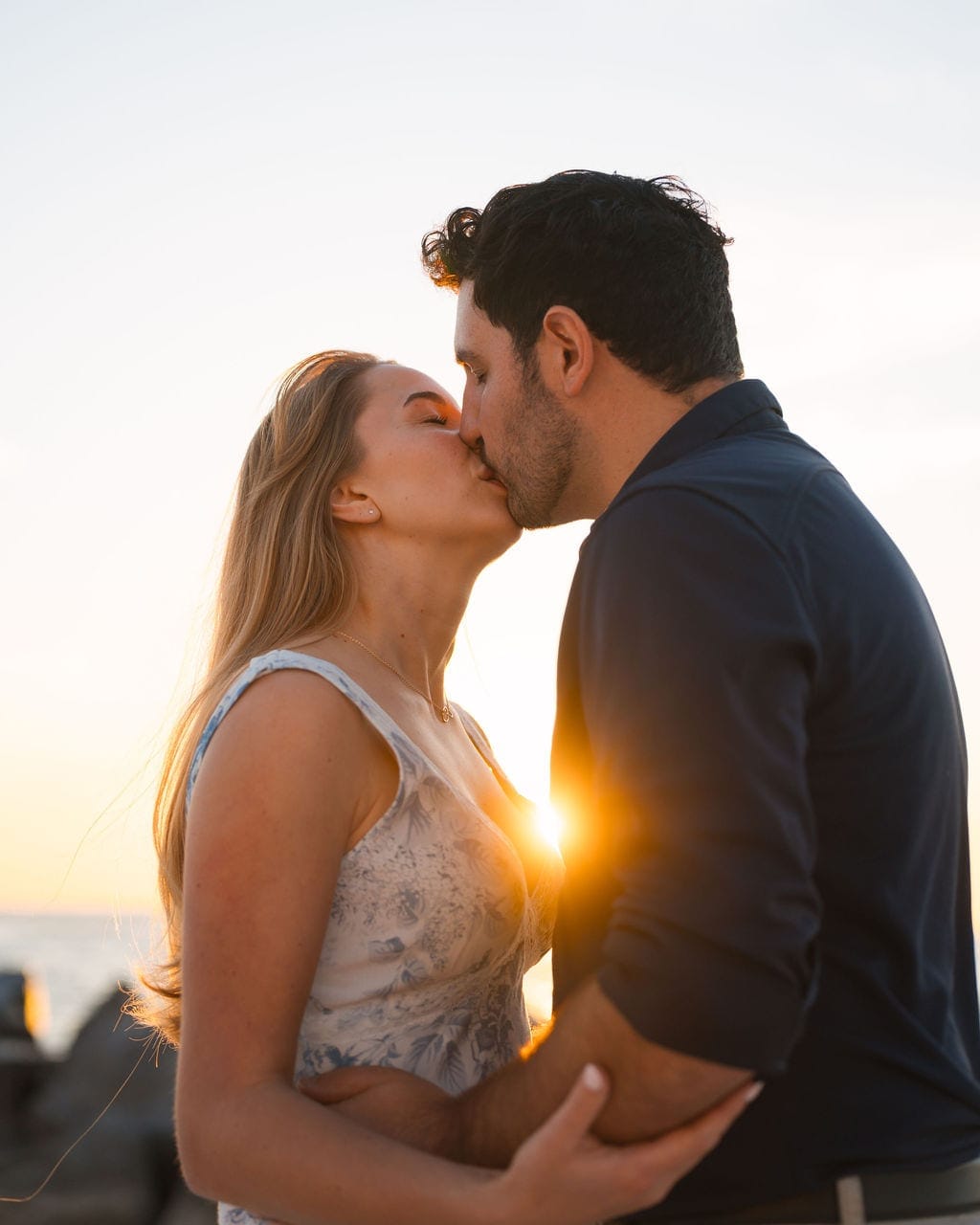 Engaged couple kissing sunburst golden hour beach Tampa
