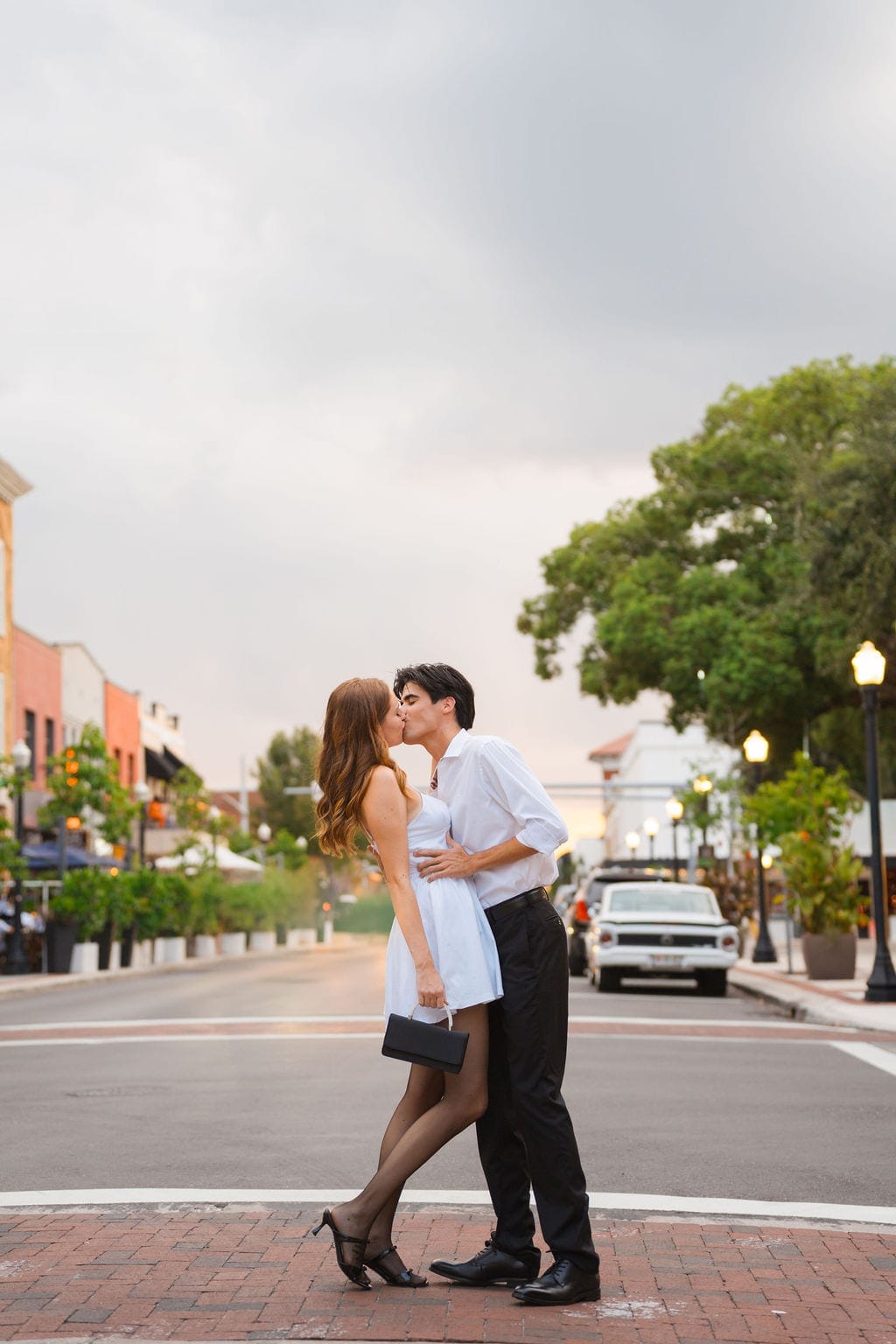Couple kissing in empty downtown street at dusk engagement