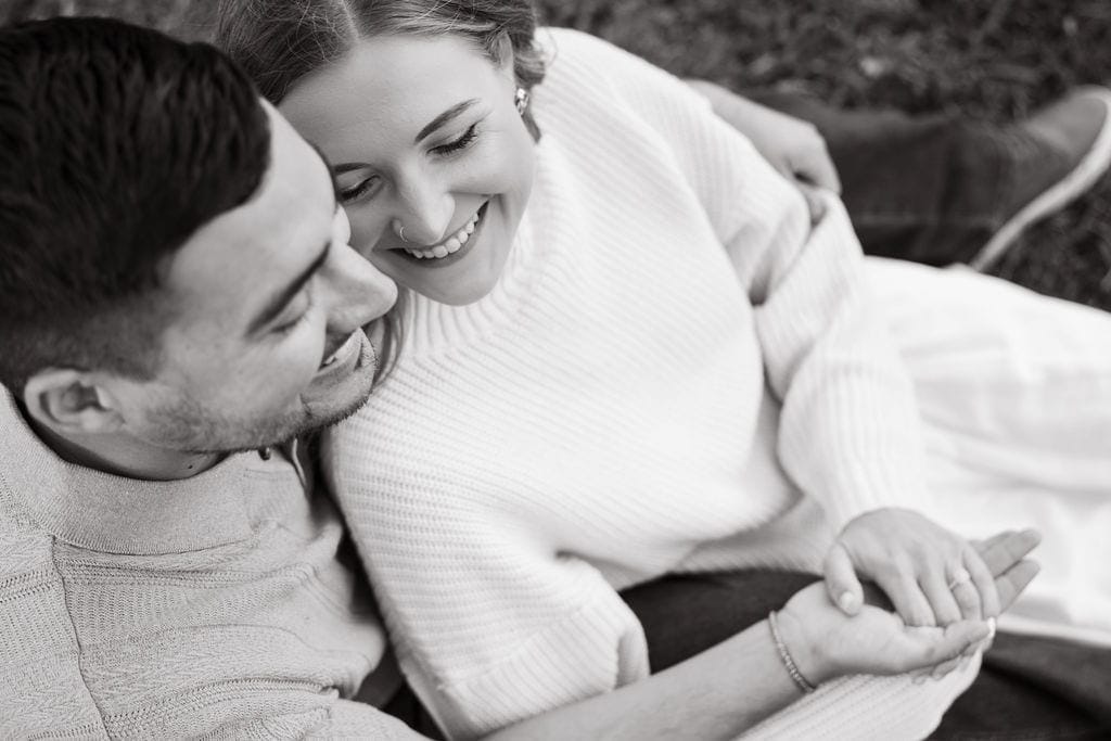 Black and white couple laughing engagement ring hands