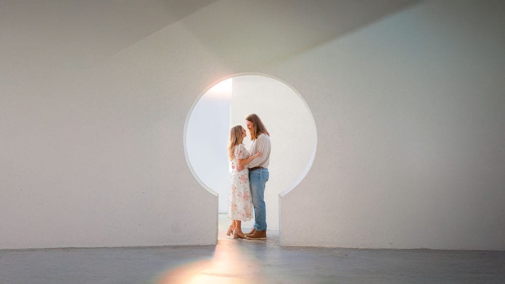Couple embracing in glowing circular doorway white walls