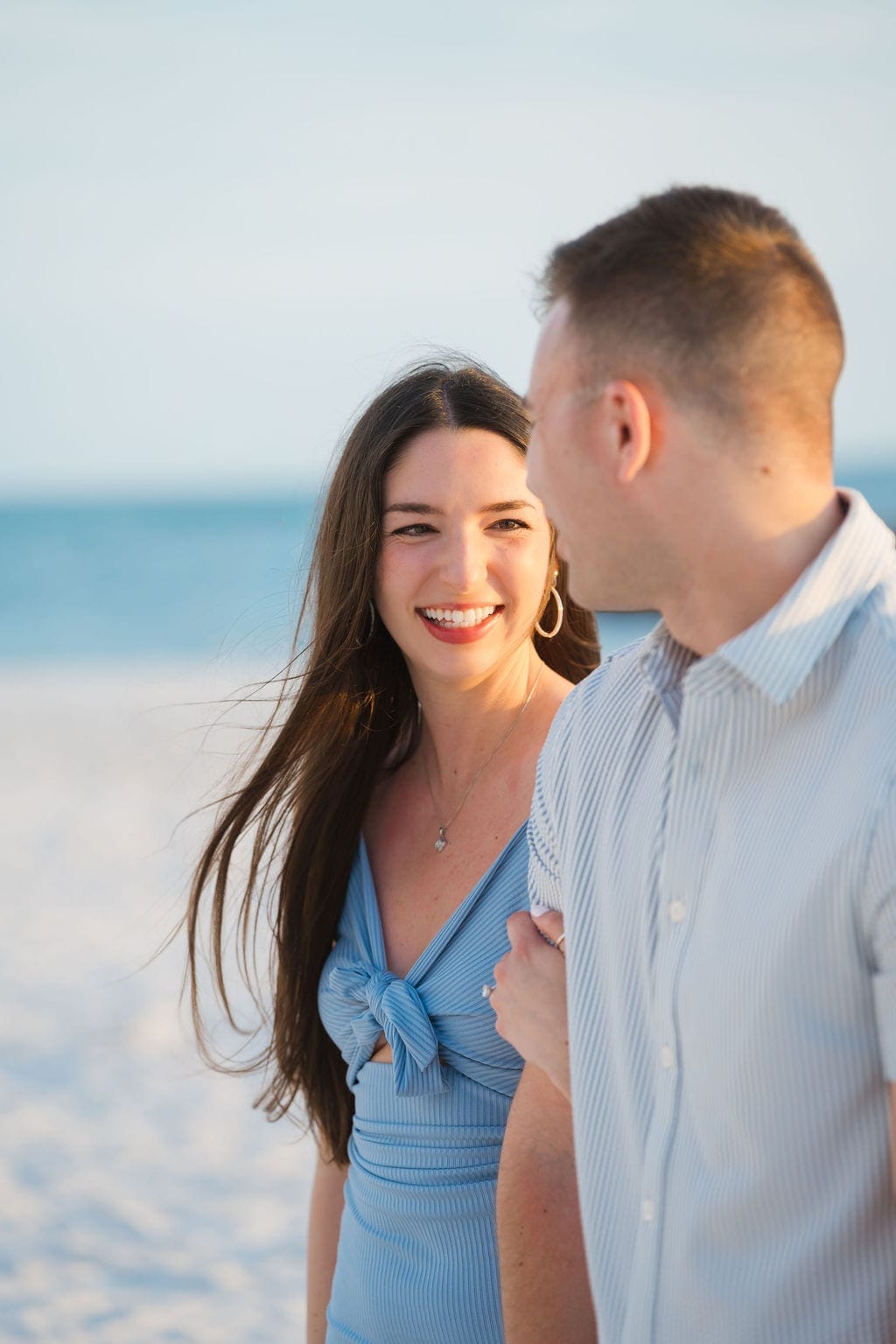 Bride to be laughing at fiance blue dress golden hour beach