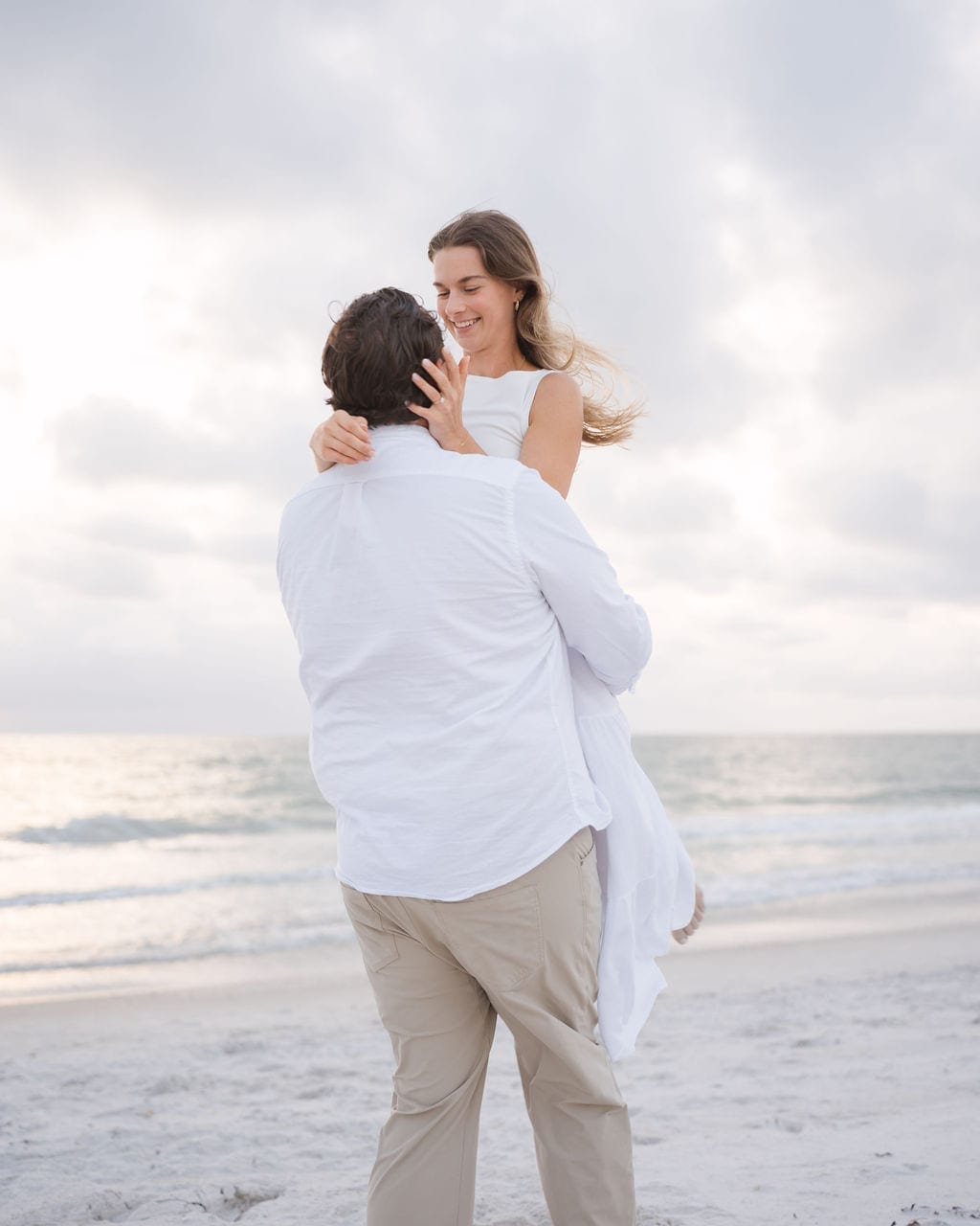 Fiance lifting partner white outfits gulf coast beach