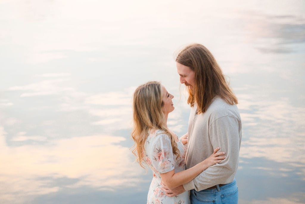 Couple laughing face to face pastel lake sunset reflection