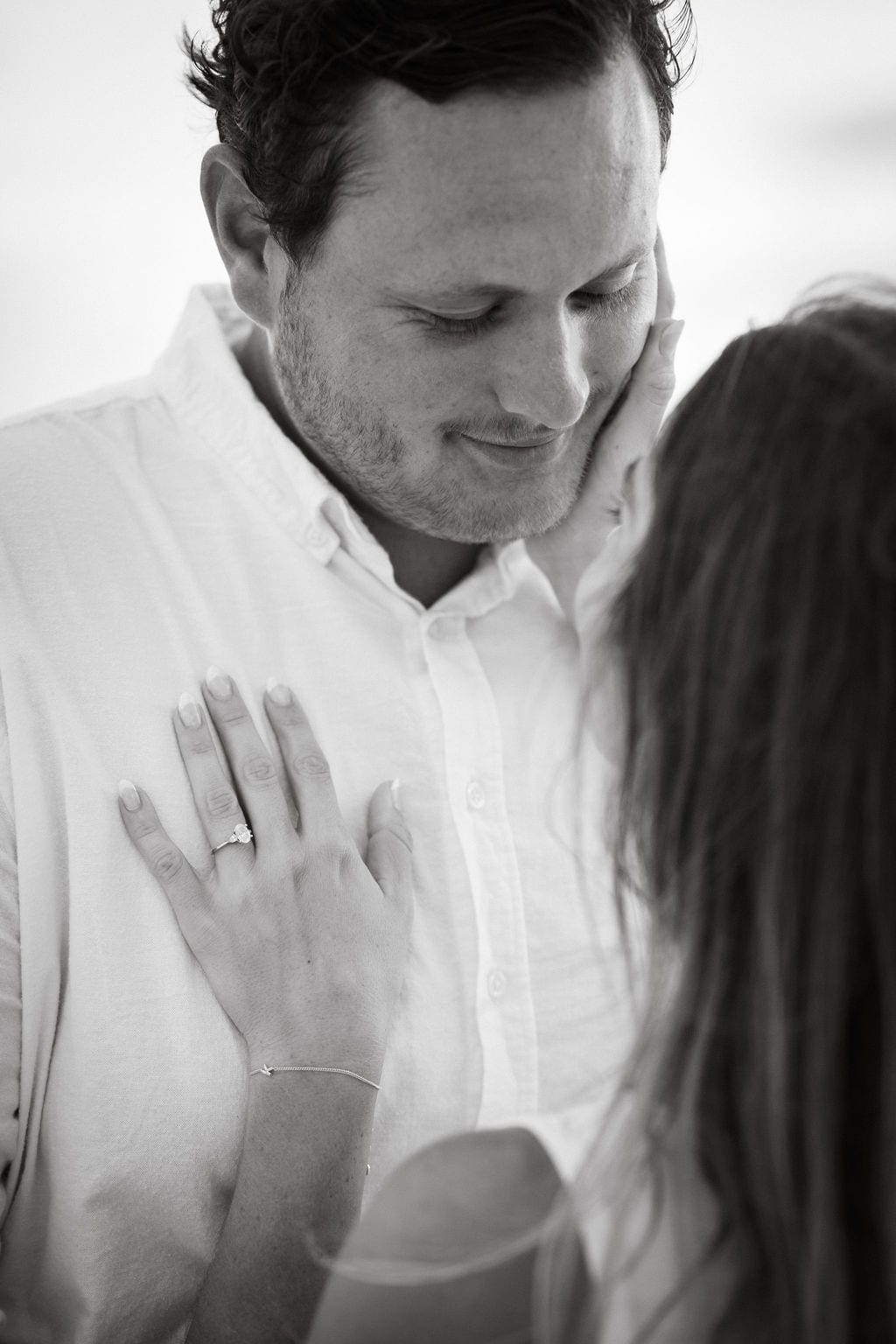 Black and white couple nose to nose engagement ring hand