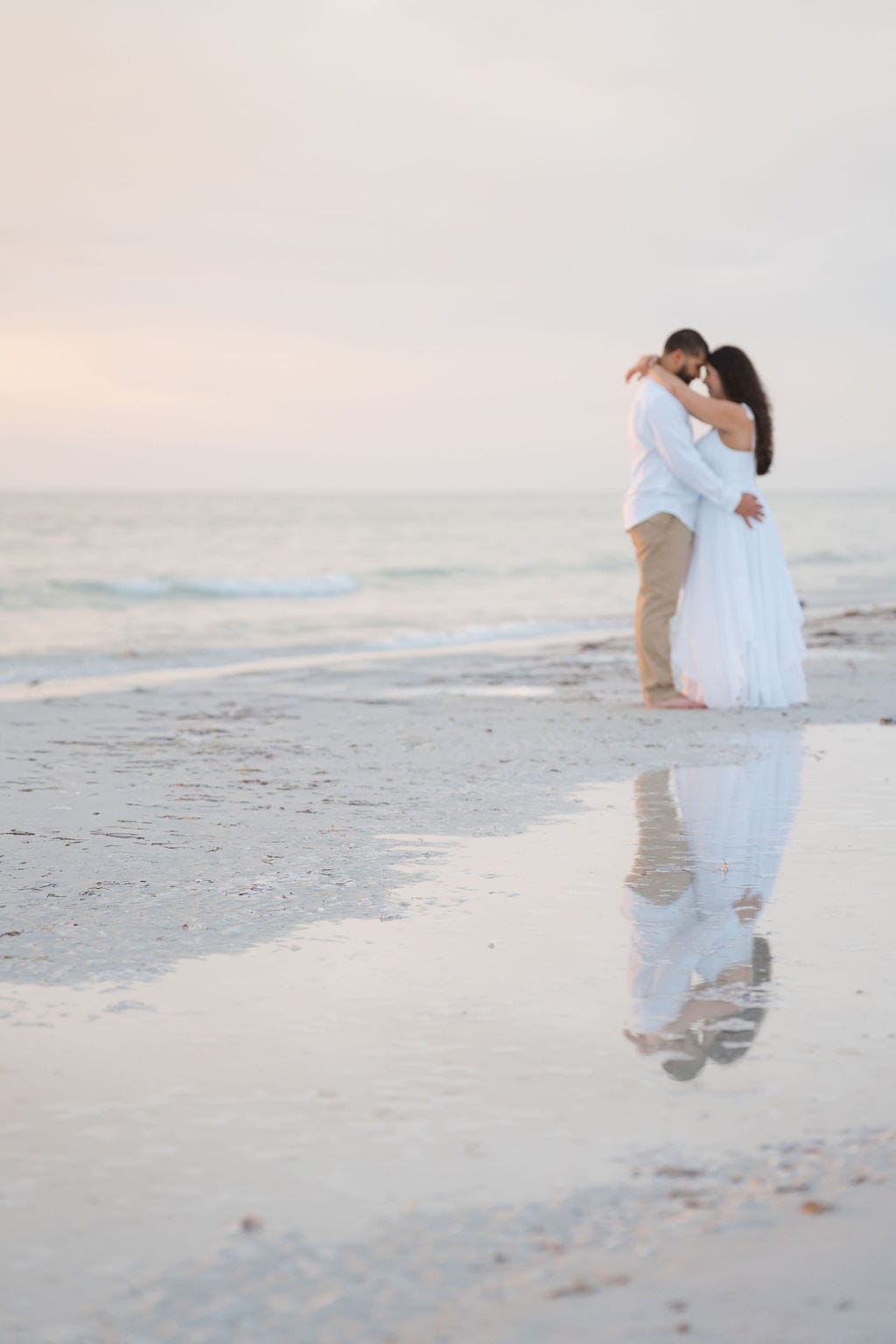 Engaged couple embracing beach reflection pastel sunset Tampa