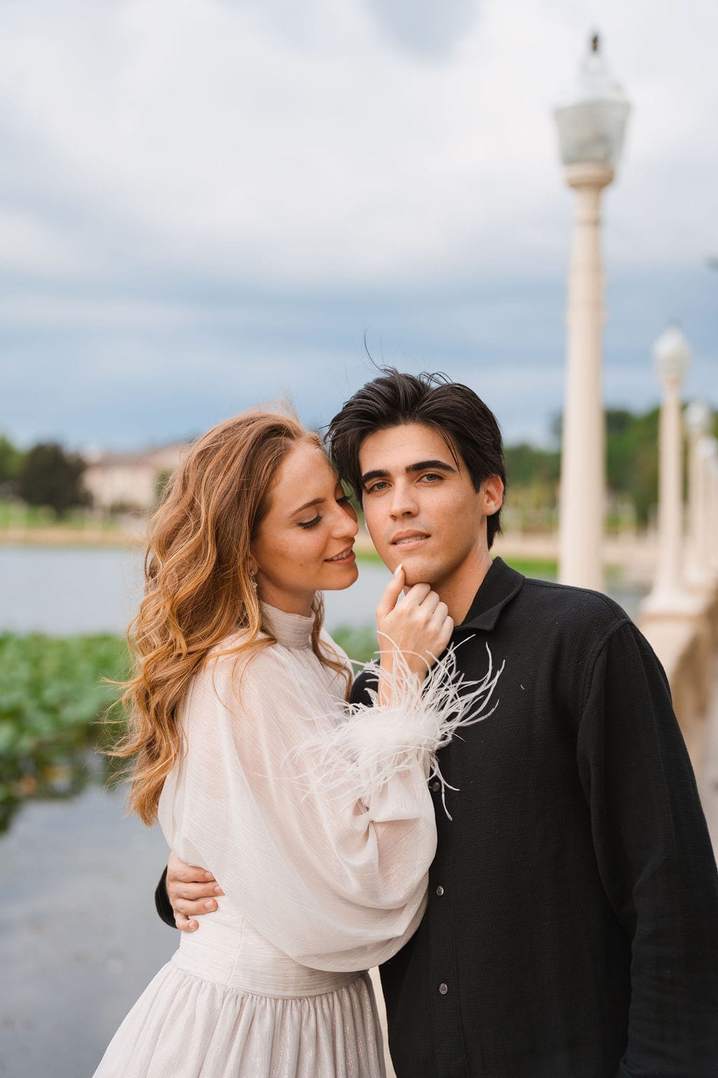 Couple portrait lakefront white feather sleeves engagement