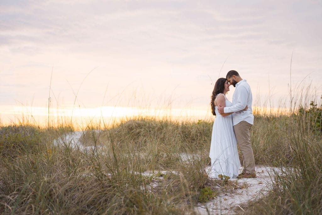 Couple foreheads together beach dunes sea oats sunset