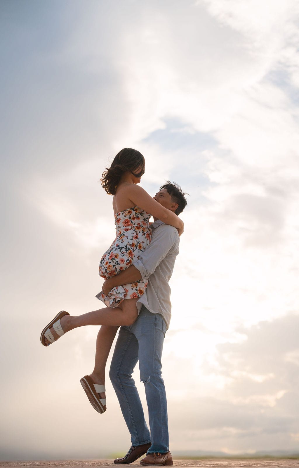 Fiance lifting partner against open sky low angle beach