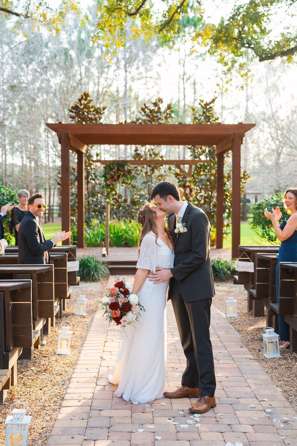 Bride and groom kiss in aisle after outdoor ceremony
