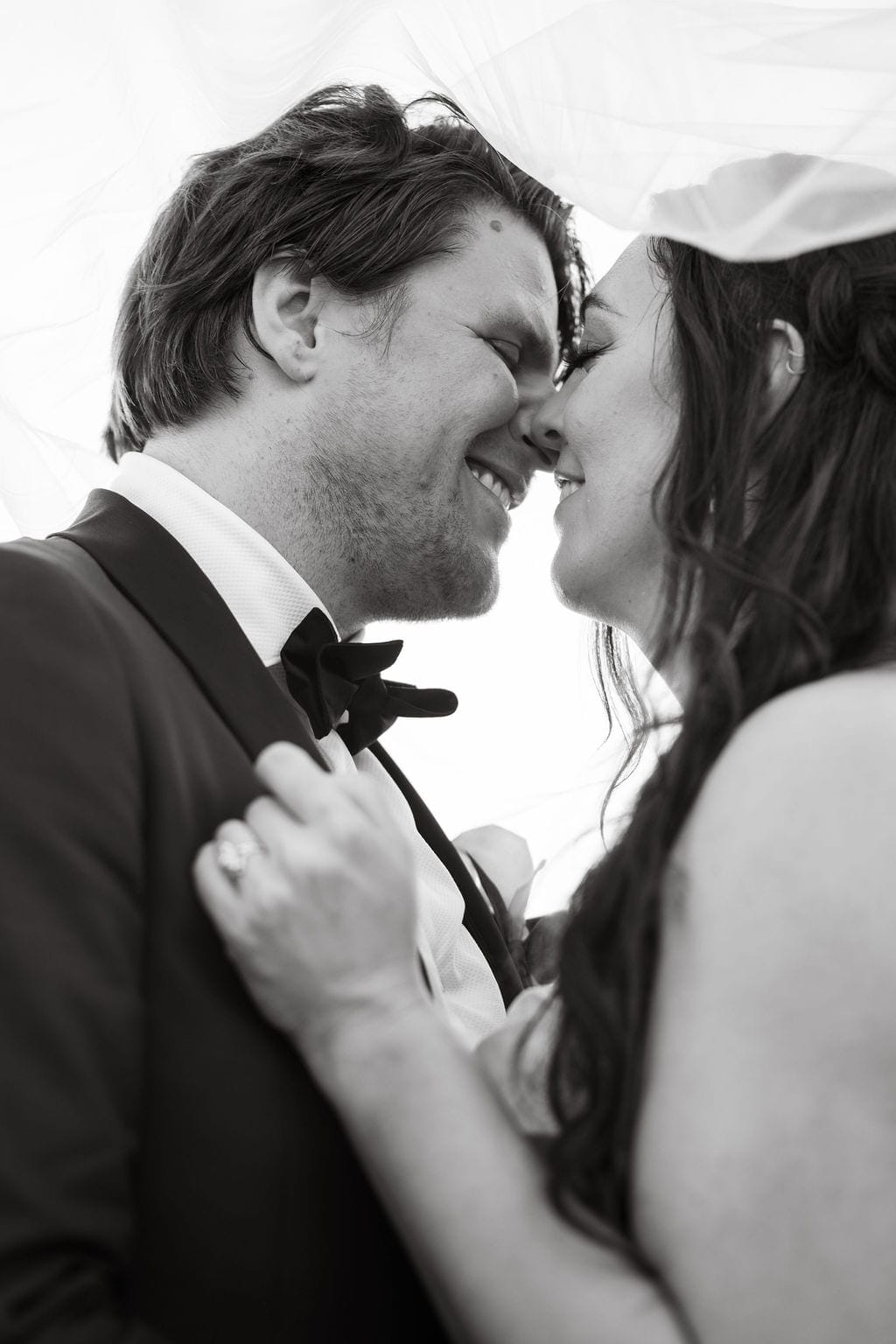 Black and white bride and groom nose to nose under veil