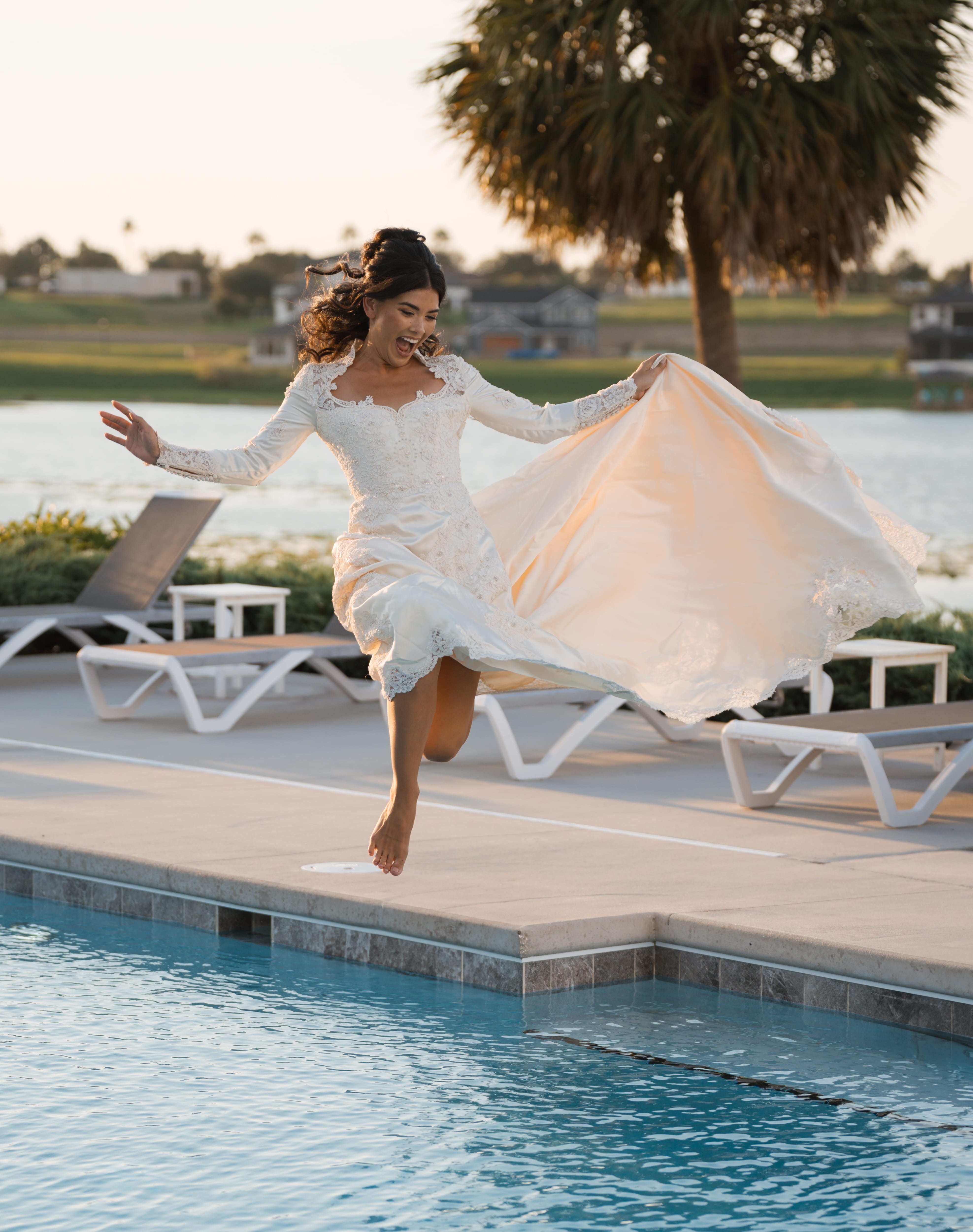 Bride jumping into pool lace gown