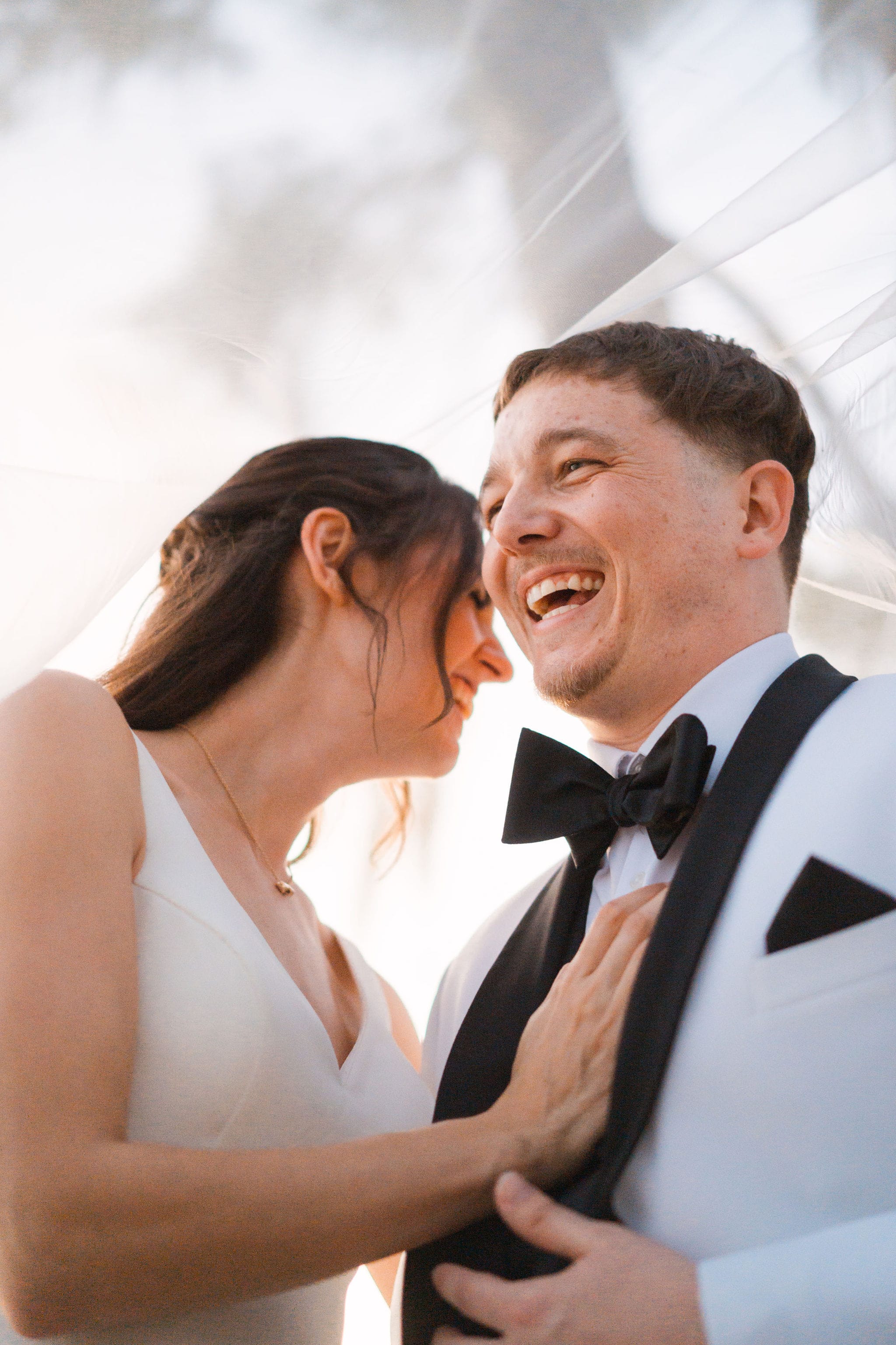 Under veil laughing couple golden backlight