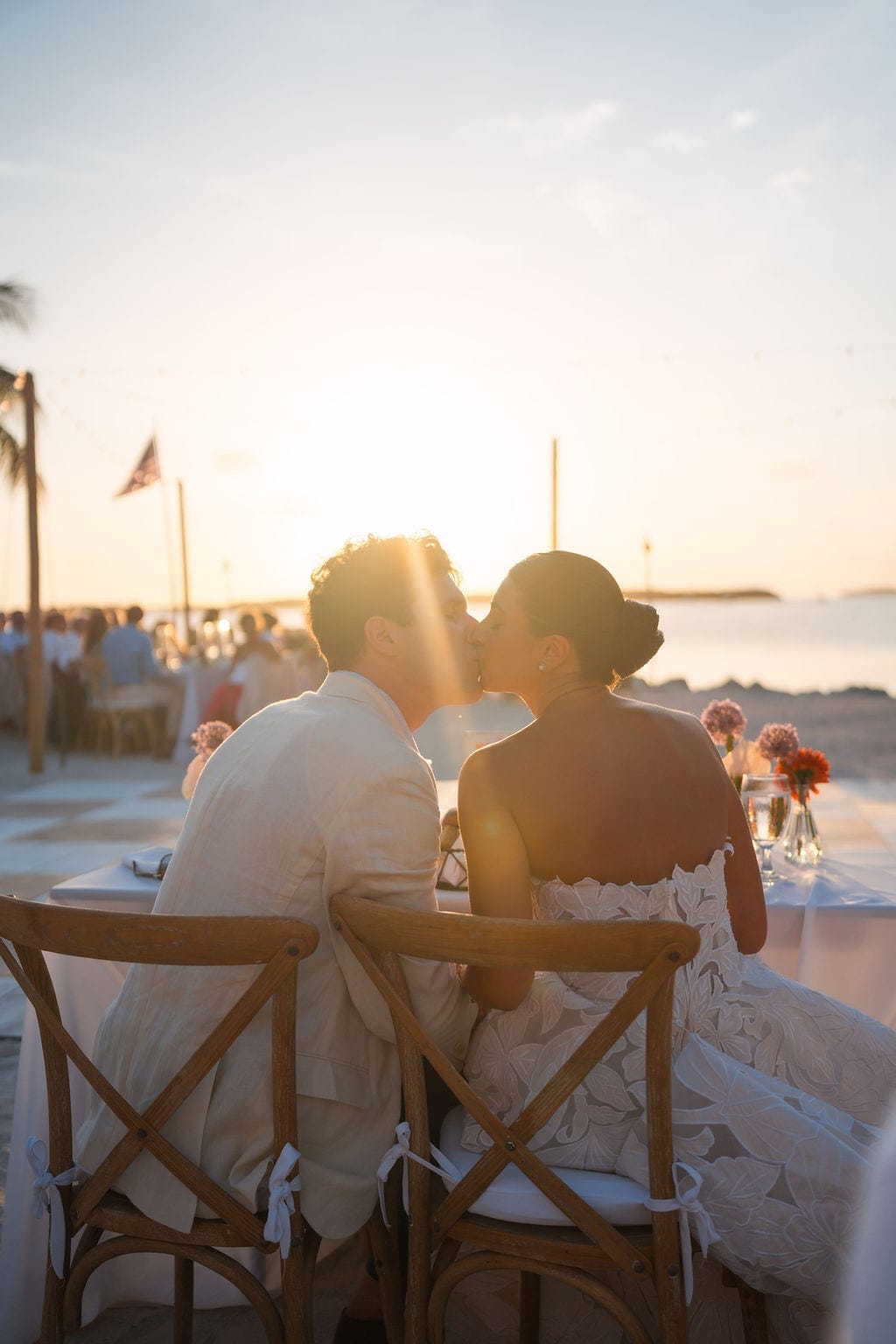 Bride and groom kissing sweetheart table sunset beach reception