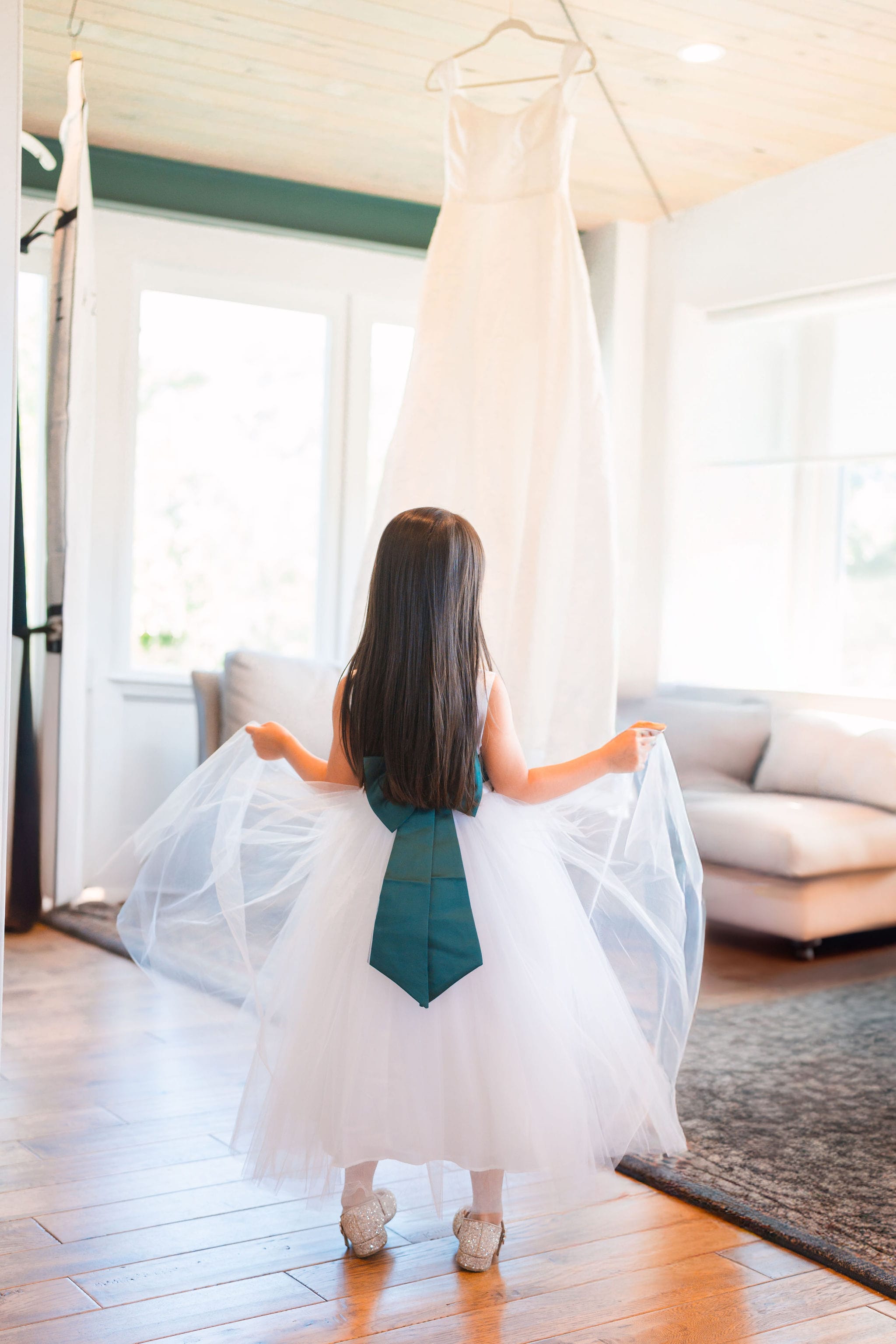 Flower girl gazing at hanging bridal gown