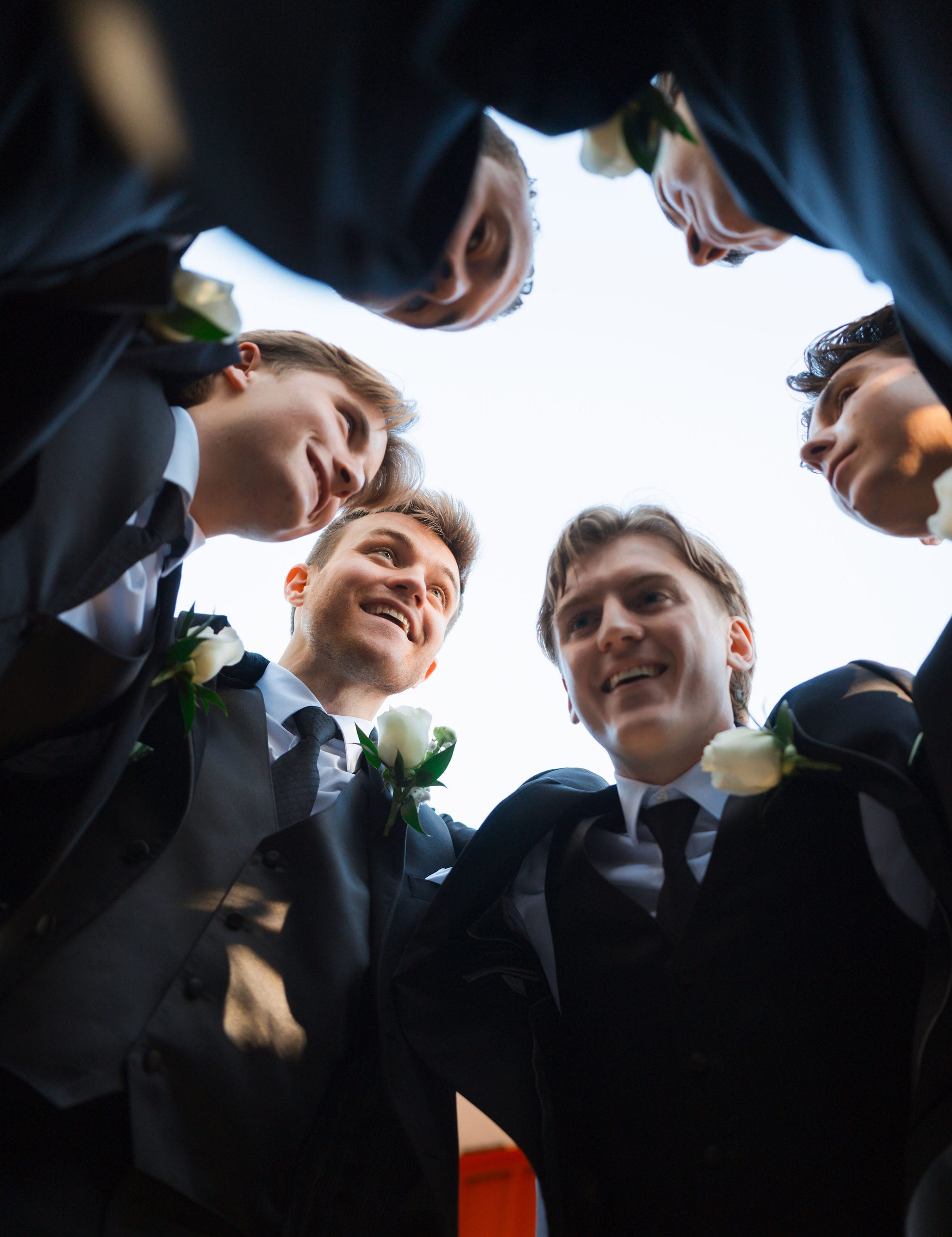 Groomsmen huddle from below black suits