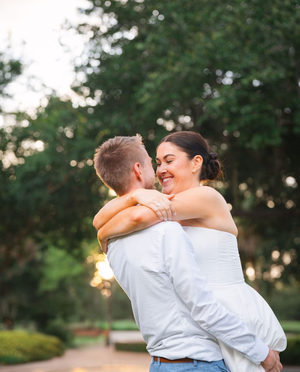 Groom lifting bride garden golden hour embrace