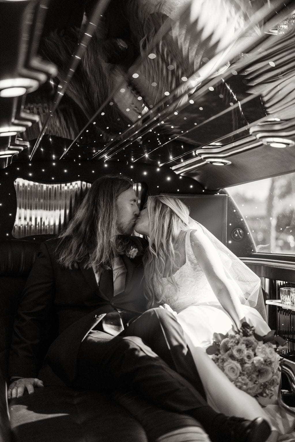 Bride and groom kissing inside limousine black and white