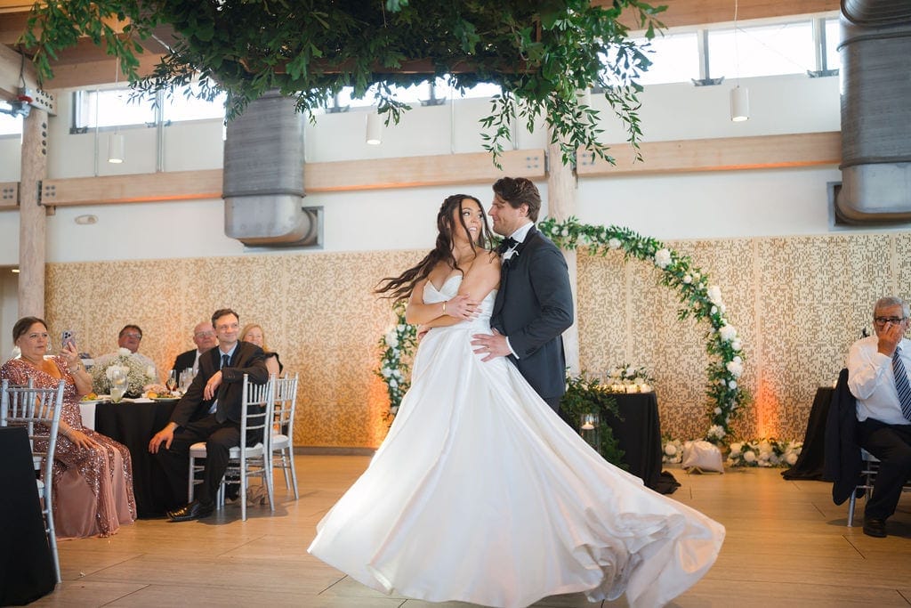 Bride and groom first dance skirt twirling greenery ballroom