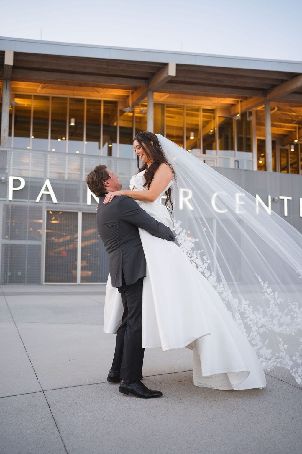 Groom lifts bride cathedral veil Tampa river center sunset
