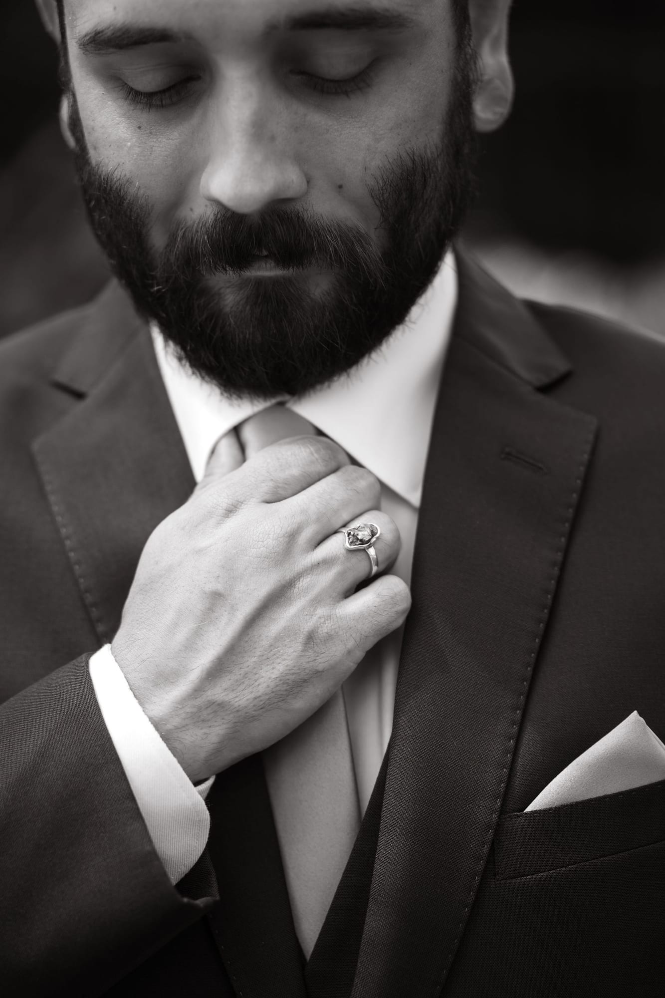 Groom adjusting his tie before the wedding, black and white
