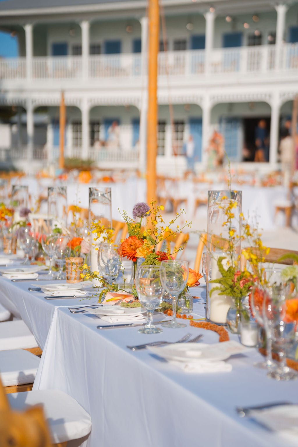 Wedding reception long table with orange florals photographed before guests arrive
