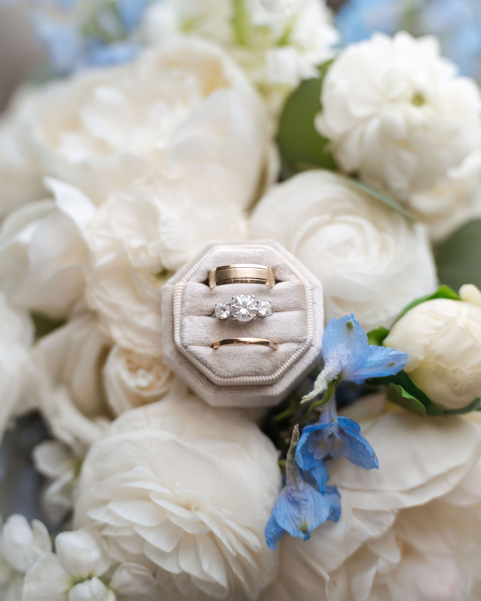 Wedding rings tucked into a white and blue bridal bouquet