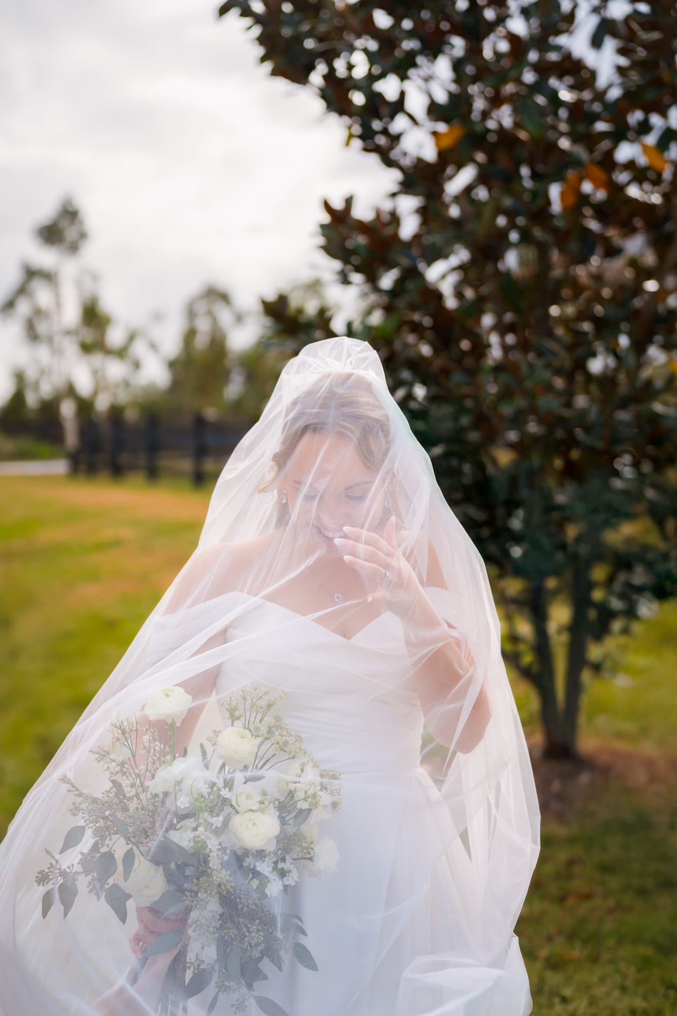 Bride standing under her veil in an open field at Mill Pond Estate