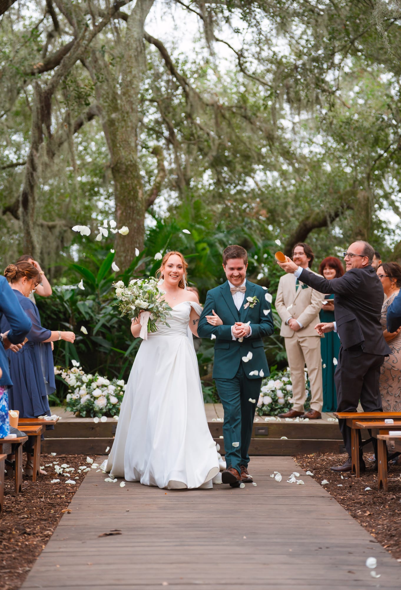 Bride walking down the aisle toward the ceremony under the oaks at Mill Pond Estate