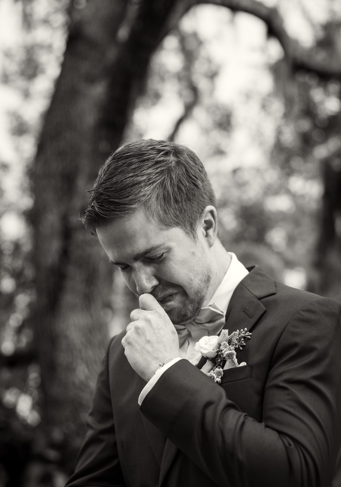 Emotional groom wiping away tears before the ceremony in black and white
