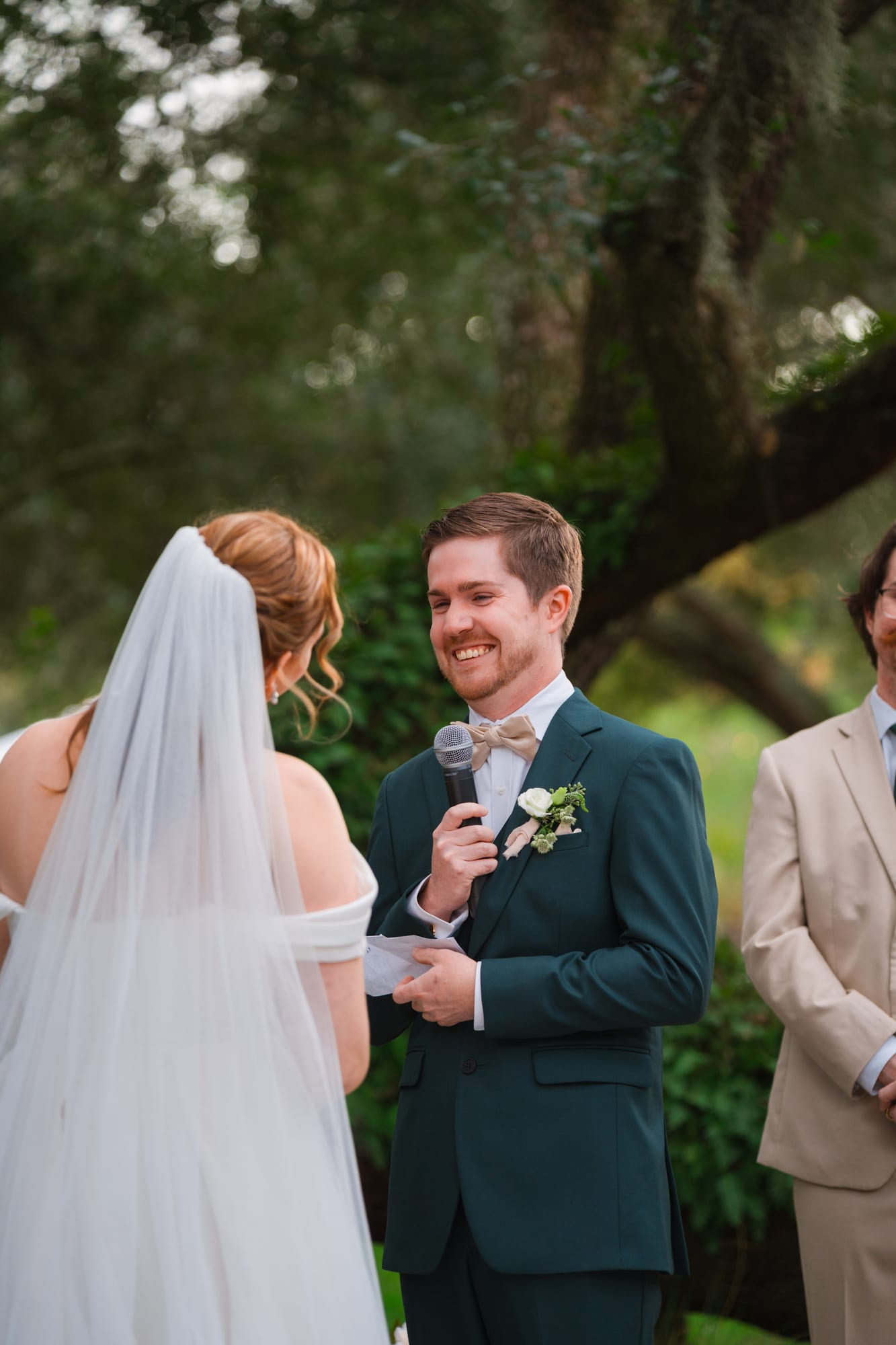 Groom reading his vows to his bride under the live oak