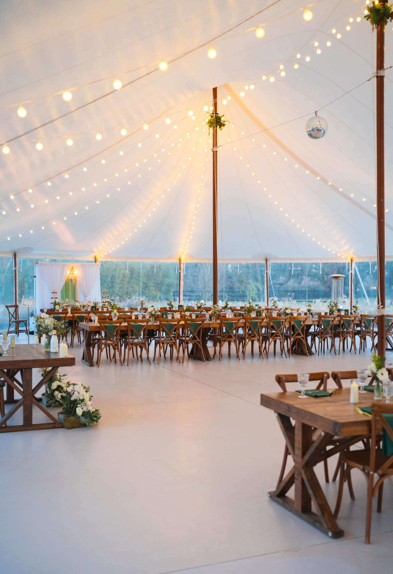 Sailcloth tent reception setup with string lights and long wooden tables at Mill Pond Estate