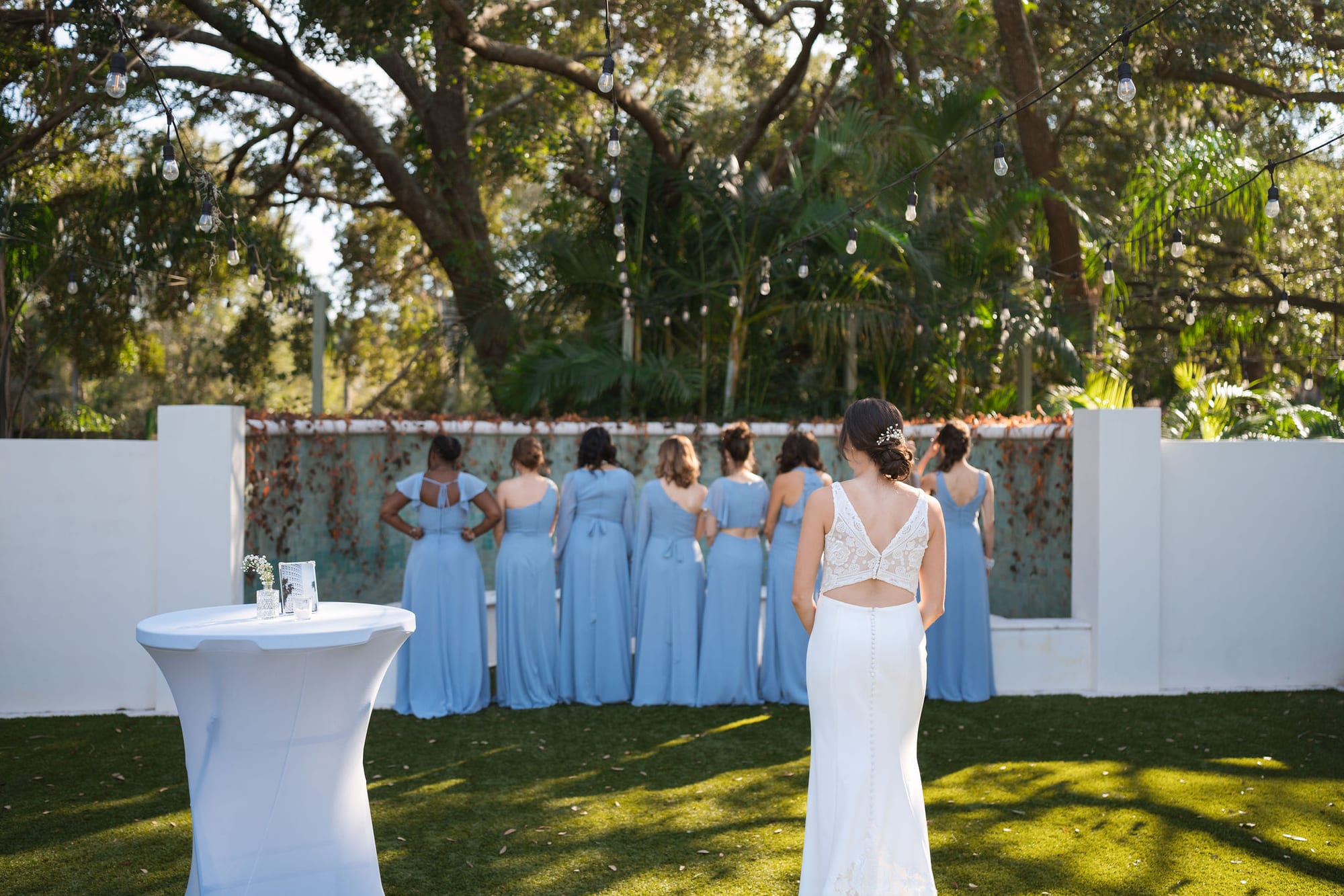 Bridesmaids in dusty blue standing with their backs turned before the bride reveal