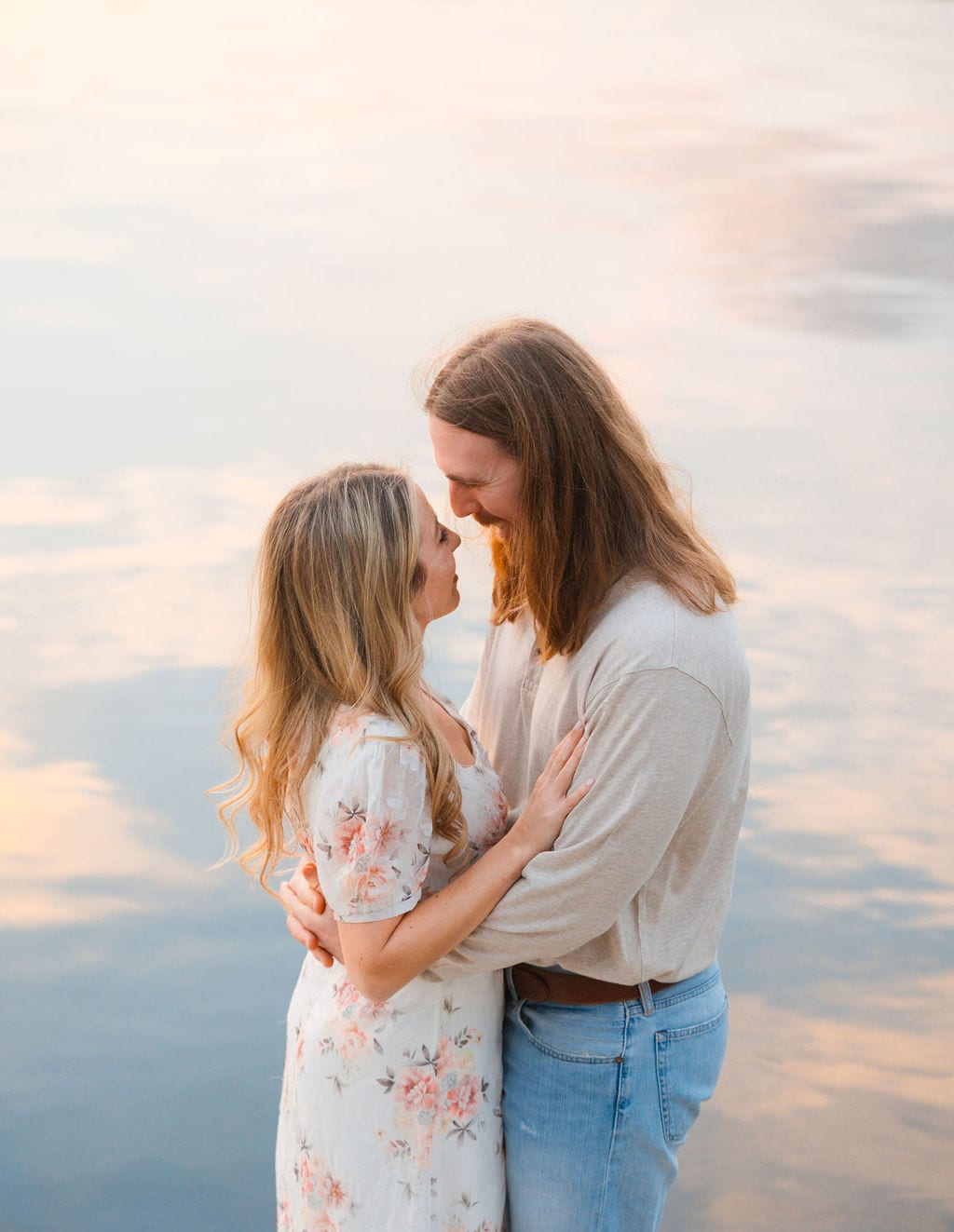 Engaged couple with noses touching at a pastel sunset with water reflection near Sarasota