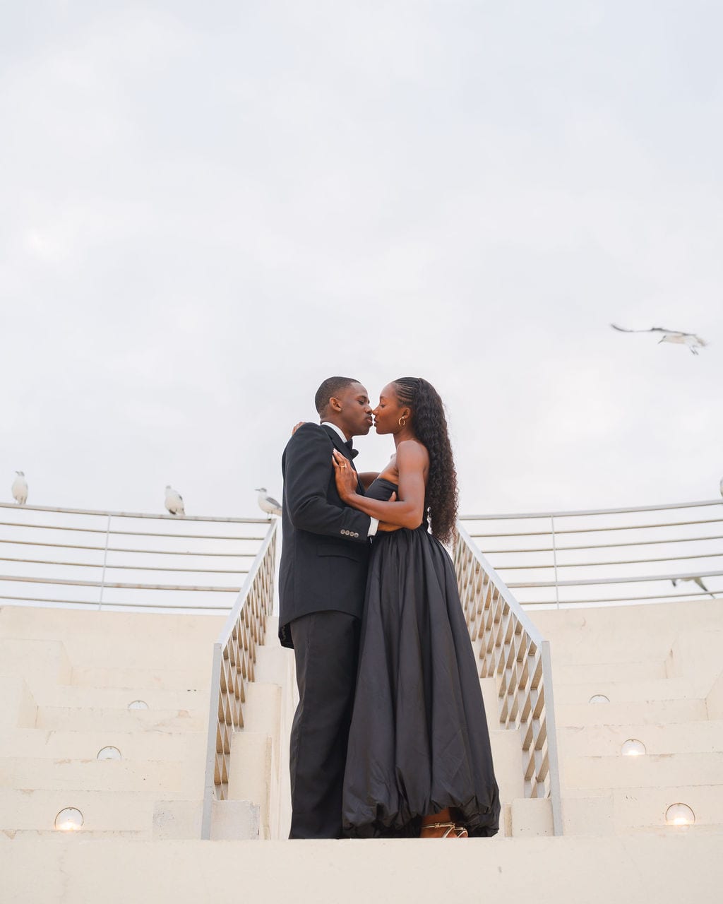 Couple kissing on white amphitheater steps at a waterfront park