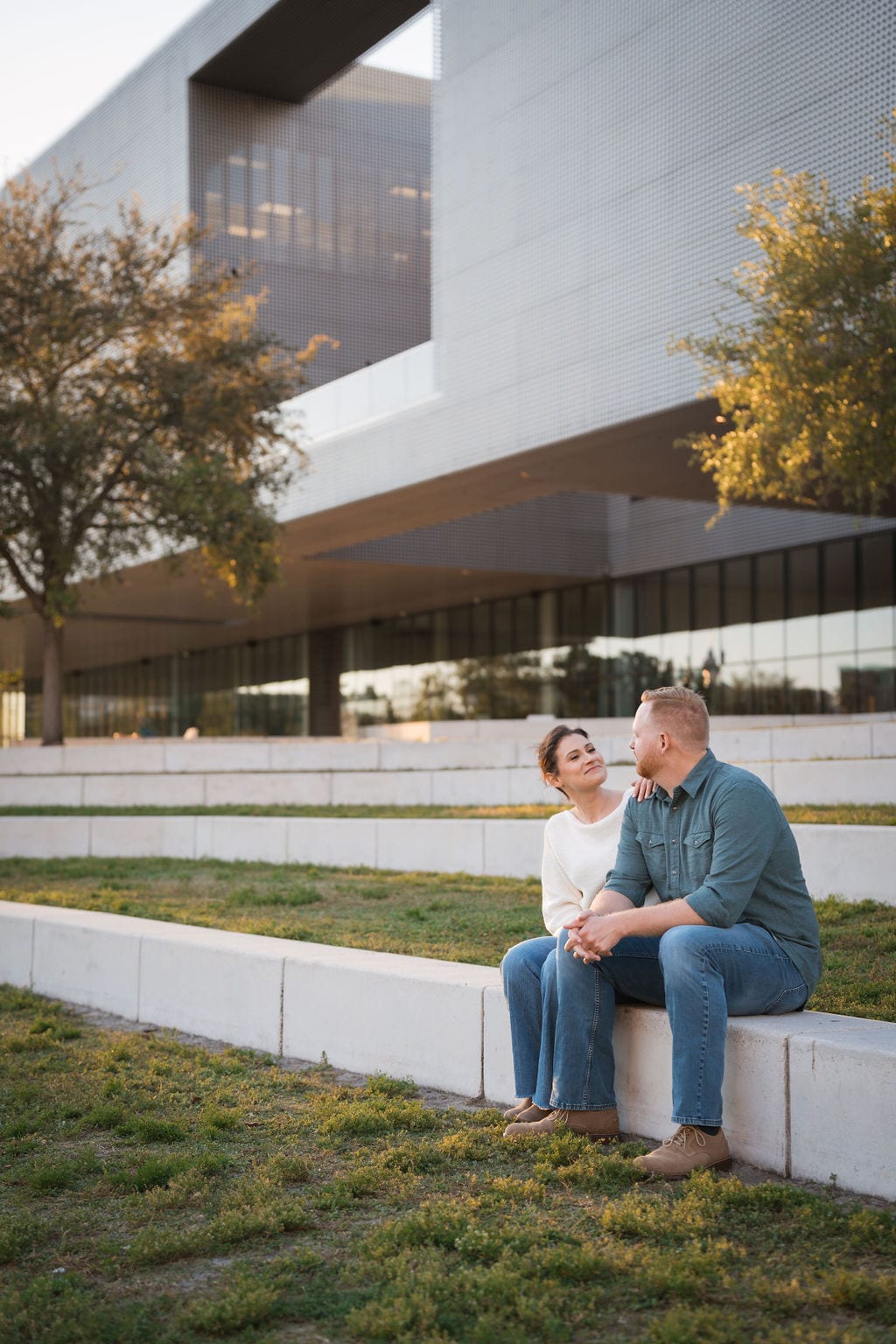 Couple sitting on museum steps with modern architecture during a St. Petersburg area engagement session