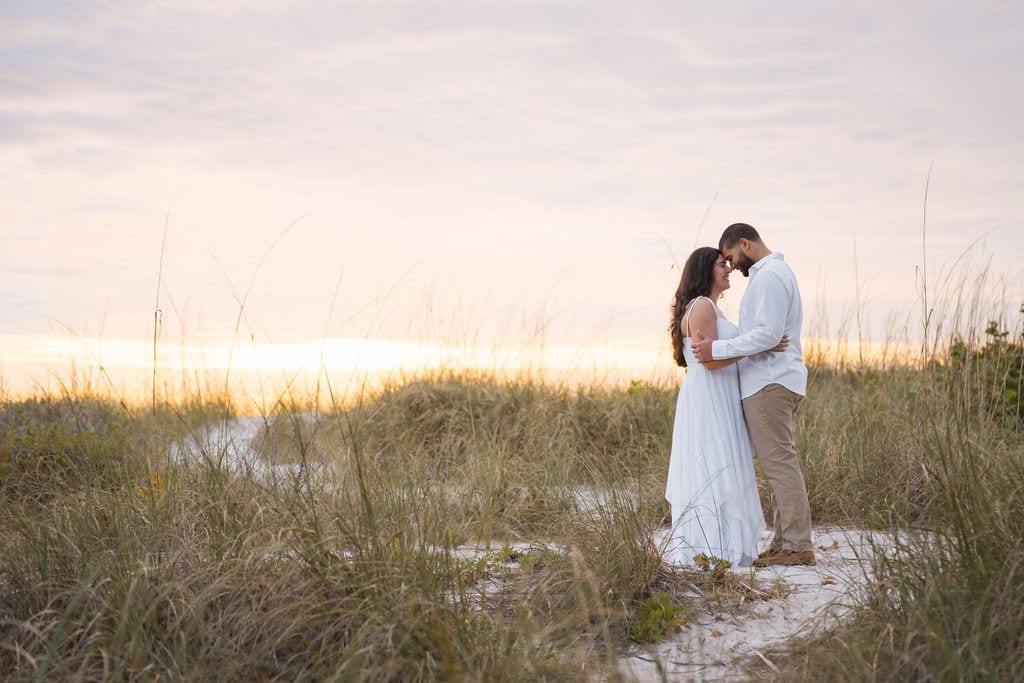 Couple with foreheads together among sea oats and dunes at a Gulf beach near Clearwater